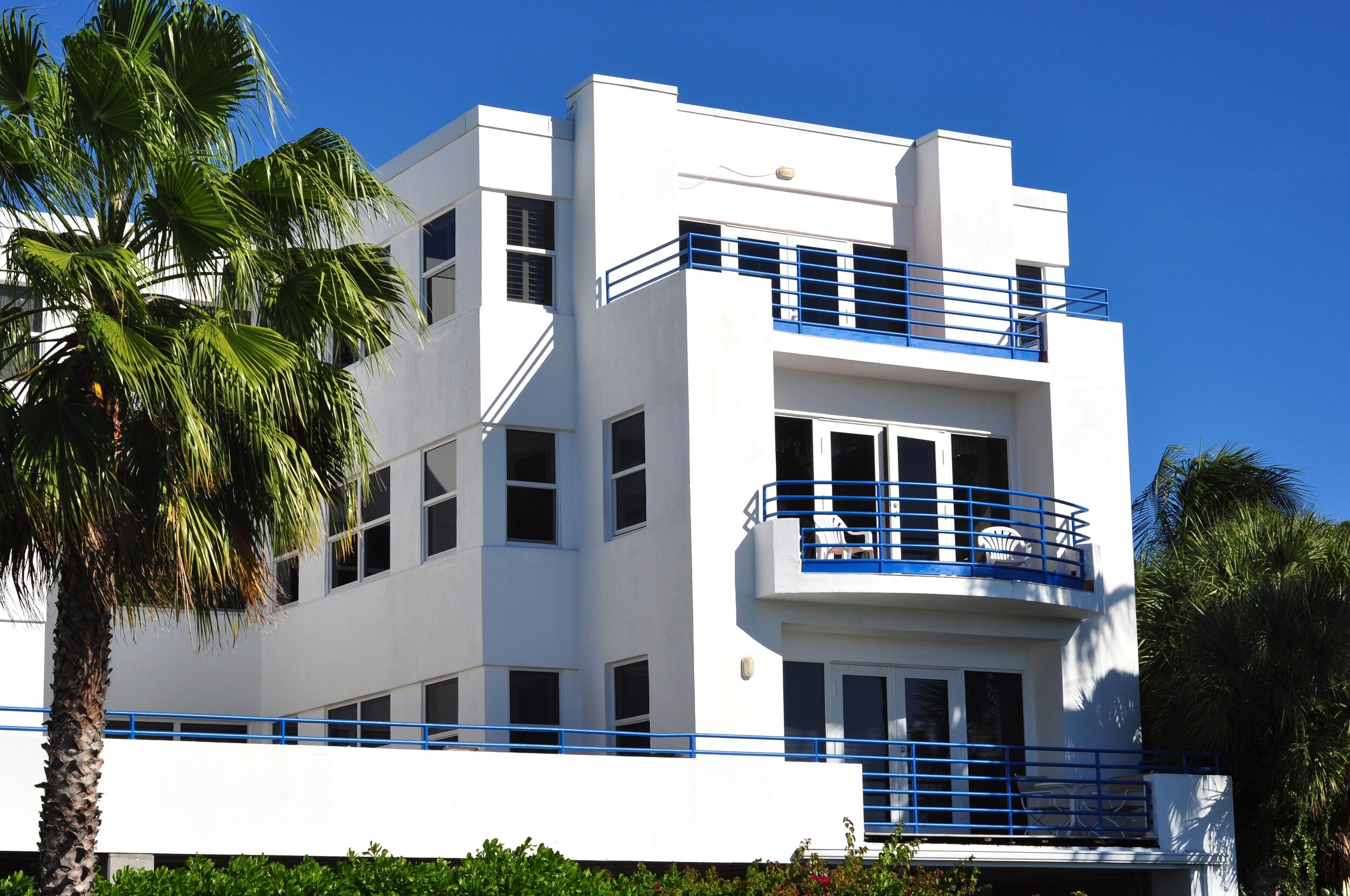 Exterior view of a condominium building with a palm tree in the foreground.